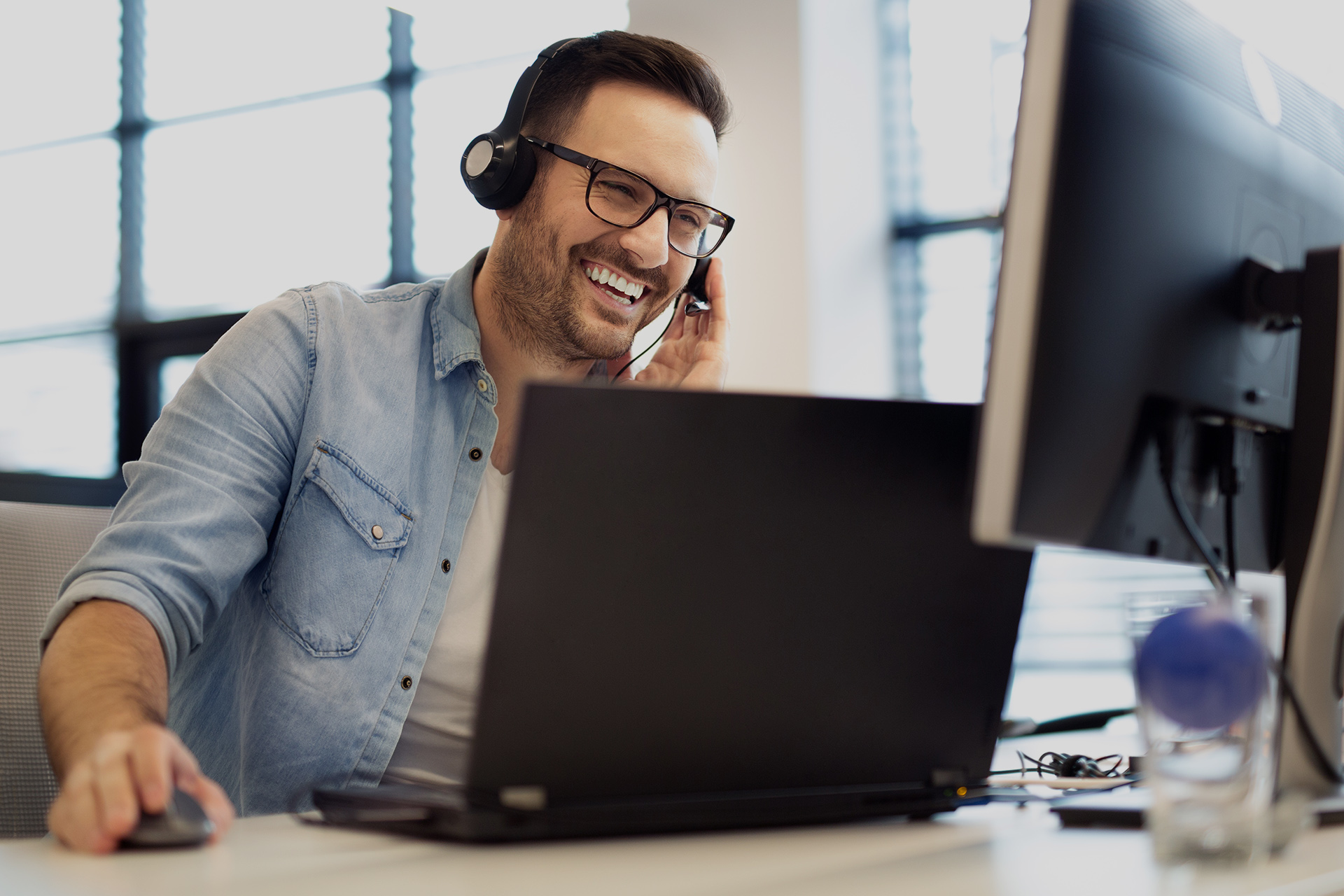 A male call center operator is talking on a phone to a customer.